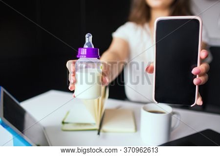 Young Woman In Kitchen During Quarantine. Cut View Of Girls Hands Hoding Baby Bottle With Milk And S