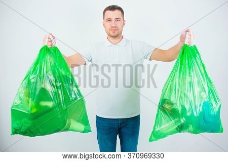Young Man Isolated Over White Background. Guy Hold Two Plastic Bags With Trash And Waste Inside It. 