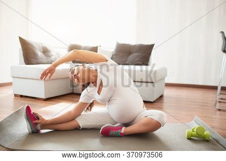 A Pregnant Woman Works Out On A Yoga Mat At Home. Pregnancy And Sports. Oga And Pilates For Pregnant