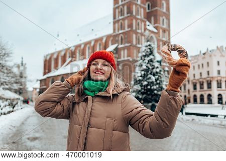 Xmas Tourist Woman In A Bright Hat And Warm Jacket Holding Baked Obwarzanek Traditional Polish Cuisi