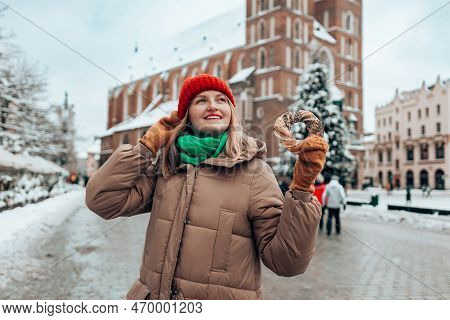 Xmas Tourist Woman In A Bright Hat And Warm Jacket Holding Baked Obwarzanek Traditional Polish Cuisi