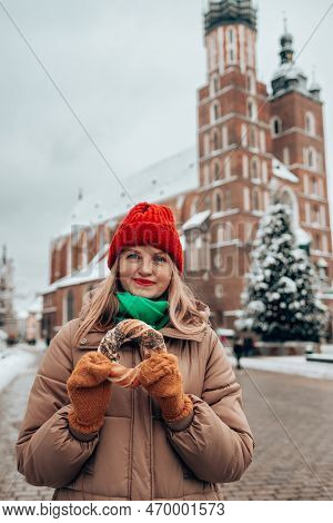 Xmas Tourist Woman In A Bright Hat And Warm Jacket Holding Baked Obwarzanek Traditional Polish Cuisi