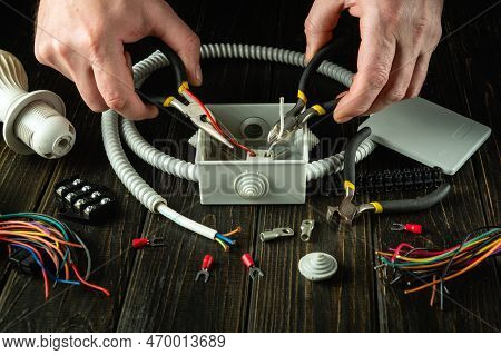 Installing A Cable Or Wire To Grey Junction Box. Master Electrician During Work. Idea For The Instal