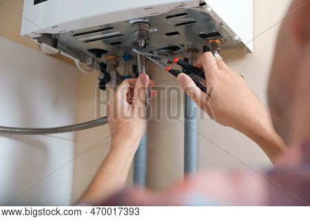 Man Repairing Gas Boiler With Waterpump Plier, Closeup