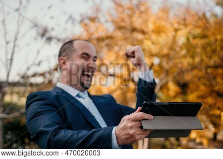 Abstrack Defocused Mature Business Man In Suit Reading A News Sitting In The Park On The Bench. Entr