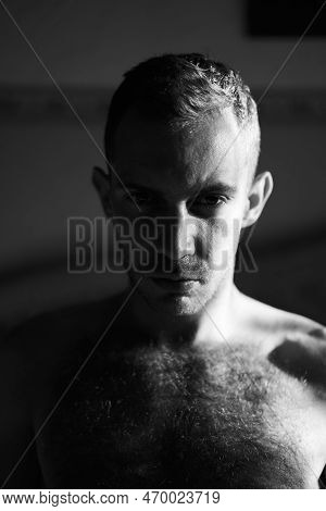 Portrait Of Handsome Man In Hard Side Light Facing Camera. Half Of Attractive Male Face Lit By The S