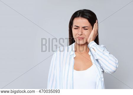 Young Woman Suffering From Ear Pain On Light Grey Background, Space For Text