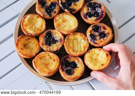 Hand Taking Pasteis De Belem, Portuguese Pastel De Nata Custard Tarts From The Plate. High Quality P