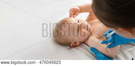 Doctor Vaccinating Smiling Baby In Clinic. One Year Little Baby Get An Injection. Pediatrician And P