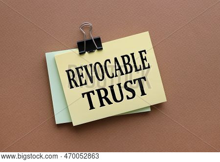 Revocable Trust Text On Yellow Sticker With Clip. On A Dark Background. Brown