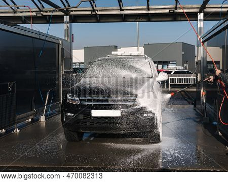 Cleaning Car On Self Service Car Wash. Man Spread Soap Using Jet Sprayer. Foam On The Car