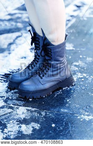 Women's Feet In High Gray Boots And White Pants In The Snow