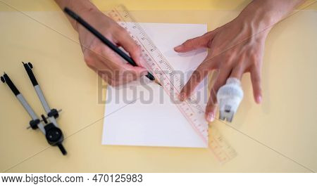 Female Hand Using A Ruler With The Pencil Preparing To Draw And Sketch On The Empty White Paper.