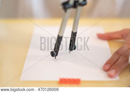 Female Hand Using A Measure Circle Preparing To Draw And Sketch On The Empty White Paper.