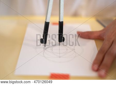 Female Hand Using A Measure Circle Preparing To Draw And Sketch On The Empty White Paper.