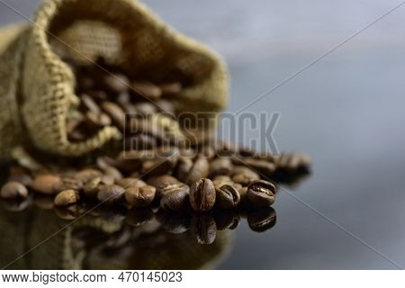 Peaberry Coffee Beans And Coffee Beans In Sack On Dark Background.  Soft Selected Focus