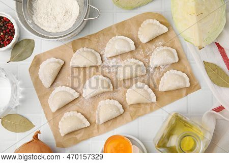 Raw Dumplings (varenyky) With Tasty Filling And Cut Cabbage On White Tiled Table, Flat Lay
