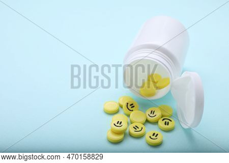 Yellow Antidepressants With Happy Emoticons And Medical Bottle On Light Blue Background, Closeup. Sp