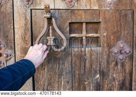 Mans Hand Knocking With A Knocker On An Ancient Wooden Door In The Medieval Town Of Pedraza, Segovia