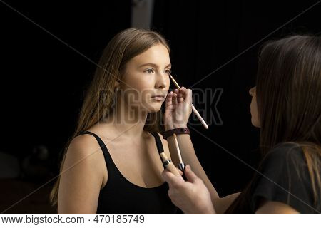 A Beautiful Young Woman With Long Hair Doing Makeup For A Wedding Or Photo Shoot. Work Of A Make-up 