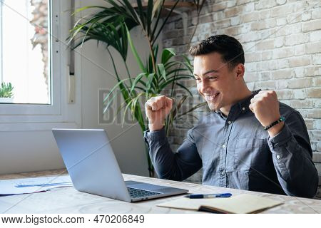 Man Sit At Desk Read E-mail On Laptop Makes Yes Gesture Feels Happy. Male Entrepreneur Get Great Bus