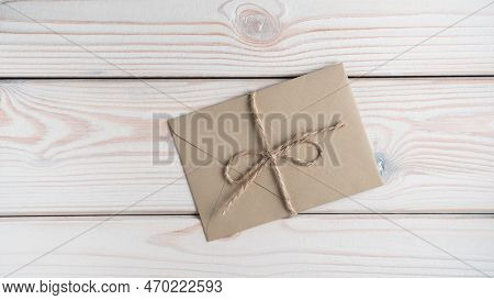 Top View Of Sealed Closed Brown Craft Envelope Tied With String Coarse Twine On Grey Wooden Table. C