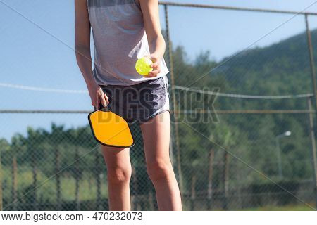 Pickleball Paddle And Yellow Ball Close Up, Woman Playing Pickleball Game, Hitting Pickleball Yellow