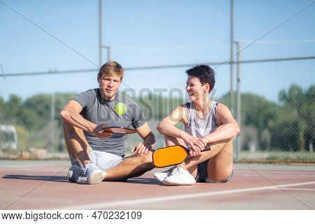 Pickleball Game, Relaxing Pickleball Players Couple With Yellow Ball With Paddle Sitting After Game,