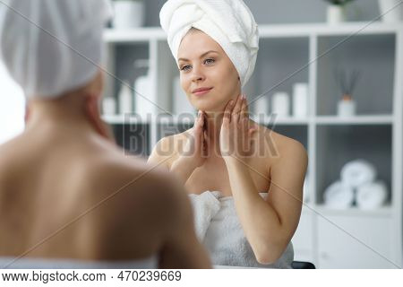 Young Woman Sits In The Bathroom In Front Of The Makeup Mirror And Does Cosmetic Procedures. Beautif