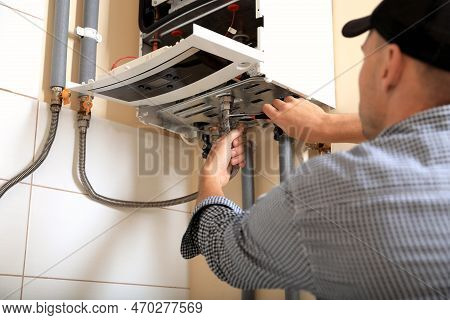 Man Repairing Gas Boiler With Waterpump Plier Indoors, Closeup