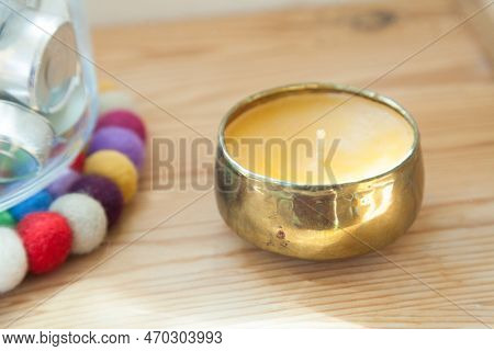 Gold Candle And Tinsha On A Wood Table.