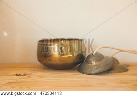 Gold candle and tinsha on a wood table.