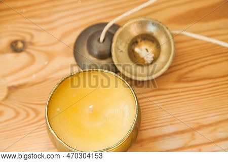 Gold Candle And Tinsha On A Wood Table.
