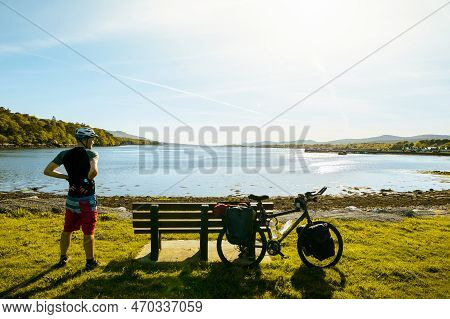 Male Cyclist Stand By Bicycle Rest In Scenic Nature By Lake Relax Enjoy Evening In Summer. Ireland C