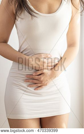 Woman Touching Her Stomach On A White Background. Abdominal Pain And Other Stomach Ailments.
