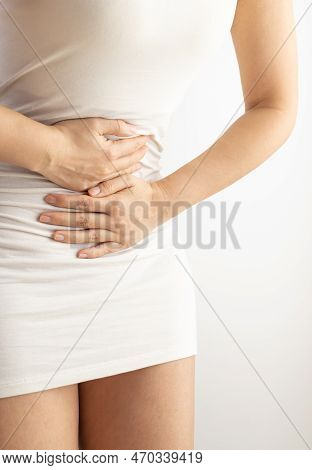 Woman Touching Her Stomach On A White Background. Abdominal Pain And Other Stomach Ailments.