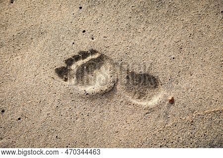 The Footprint Of A Person In The Wet Sand On The Beach.