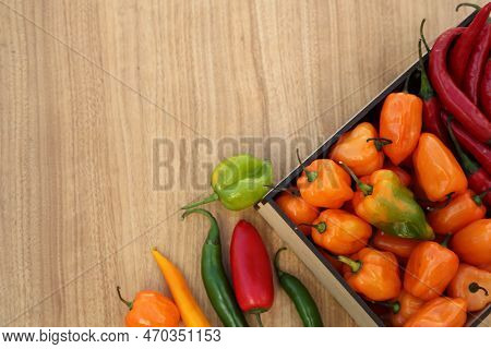 Many Different Fresh Chilli Peppers On Wooden Table, Flat Lay. Space For Text