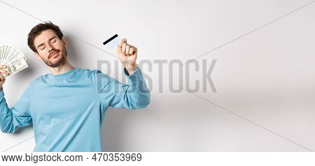 Carefree Male Model Dancing With Money And Credit Card, Smiling And Dreaming Of Shopping, Standing O