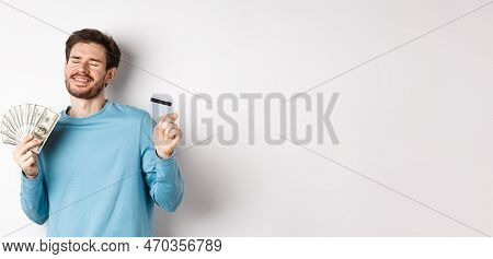 Cheerful Guy Celebrating Salary, Dancing With Plastic Credit Card And Money, Smiling Satisfied, Stan