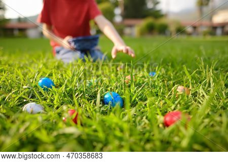 Little Boy Hunting For Multicolored Eggs In Spring Garden On Easter Day. Traditional Festival Outdoo