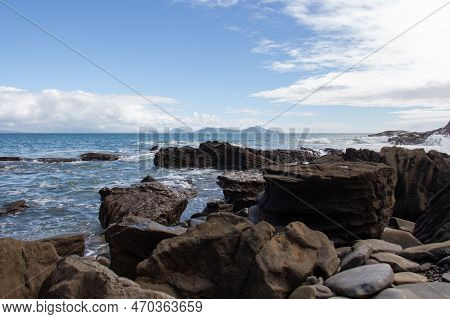 The View Of Rocky Coastline With Blue Sea And An Island On Background, Auckland, New Zealand.