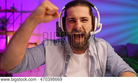 Gamer Bearded Guy, In A Gaming Headset, Wins A Video Game. Cybersportsman In A Neon Room. Lifestyle 