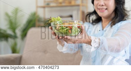 Happy Old Lady Eating Fresh Green Salad, Smiling At Home