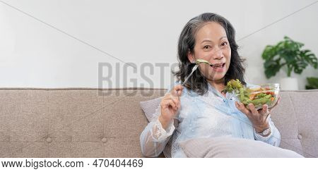Happy Old Woman Eating Healthy Vegetable Salad At Home