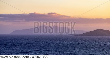 Rocky Island On Mediterranean Sea. Rinia Near Mikonos, Greece, Europe. Nature Background. Sunrise Sk