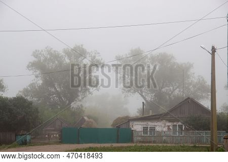 A Foggy Day In A Rural Area With Houses And Green Trees