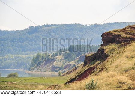 Steep Red Clay Shores Of The Lake Covered With Coniferous Forest On A Hot Summer Day