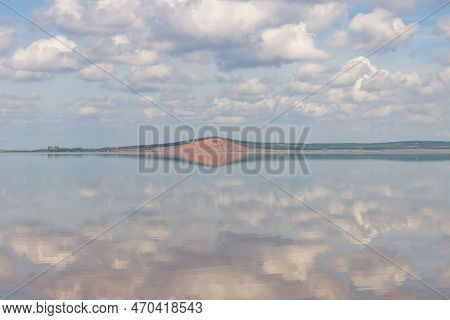 Lake With Clouds In The Sky, Red Hill With Forests On Background