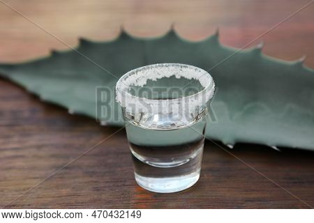 Mexican Tequila Shot With Salt And Green Leaf On Wooden Table, Closeup. Drink Made Of Agava